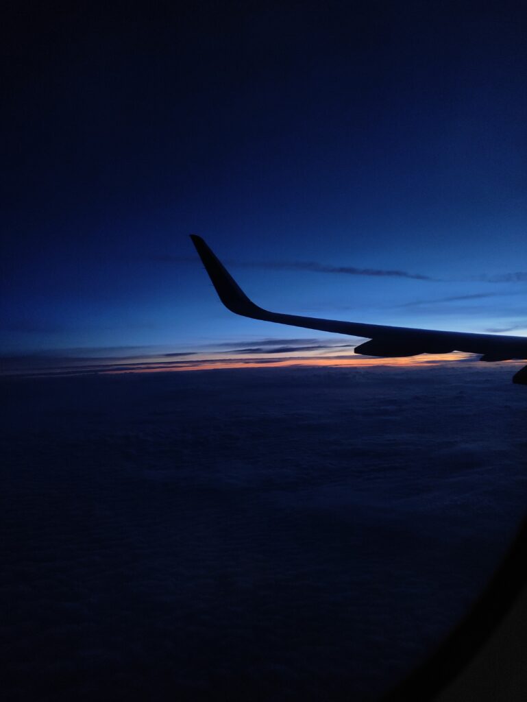 View from the airplane wing on a flight from India to Ireland, capturing the clouds and sky during my journey abroad.